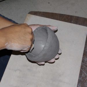 Using a piece of gourd to work the clay out from the inside