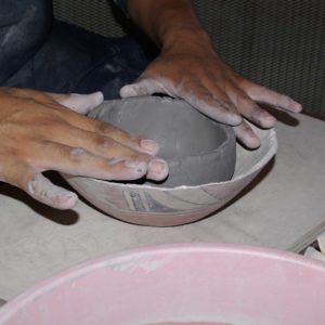 Pushing the clay into a bowl form