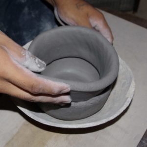 Adding the first clay coil to the bowl