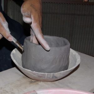 Smoothing the first clay cloil to the bowl