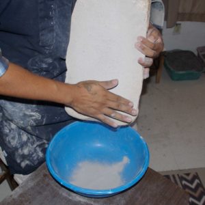 Scraping the ground clay into a bowl