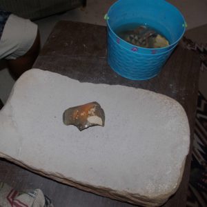 Preparing to grind a pot sherd on a metate