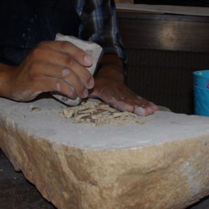 Pounding the pot sherds even finer with another stone