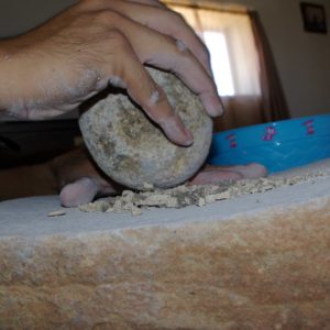 Still pounding and grinding pot sherds with a large stone