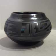 A black-on-black bowl with a four-panel geometric design around the shoulder