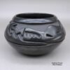 An avanyu design carved around the outside of a black bowl