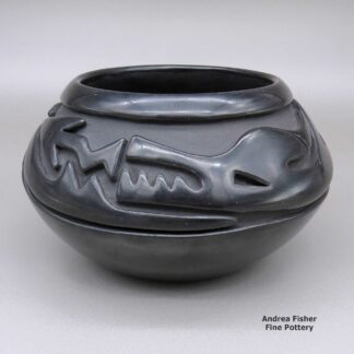 An avanyu design carved around the outside of a black bowl