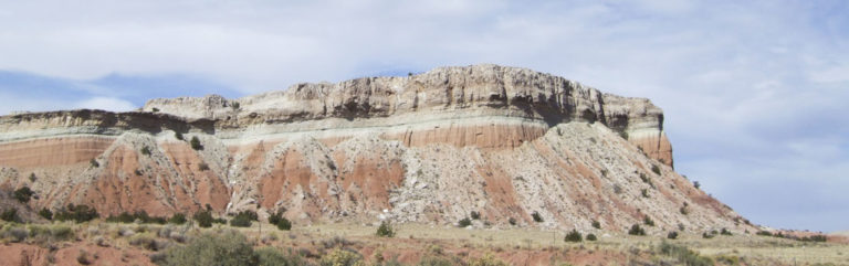 Looking at the side of a multilayered, multi-colored mesa in the desert